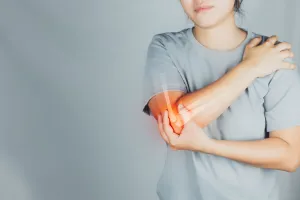 Person holding their elbow with one hand, and their shoulder with the other, indicating pain or discomfort in the arm.